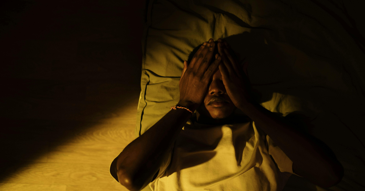 A man laying on his bed experiencing signs of depression